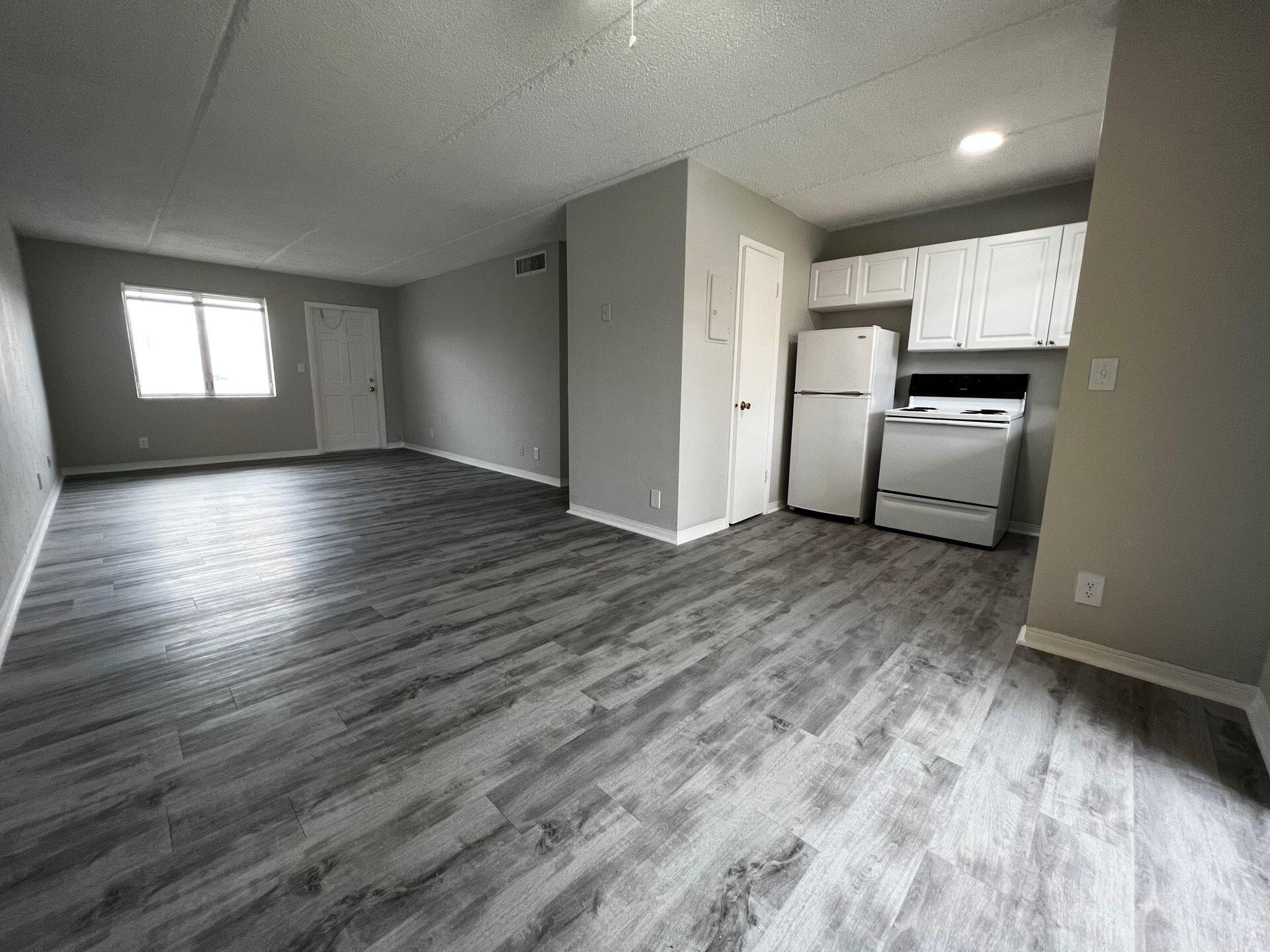 a view of a kitchen with wooden floor and a refrigerator