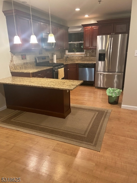 a view of kitchen with stainless steel appliances wooden floor