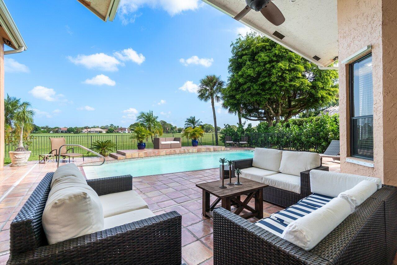 a view of a patio with couches potted plants and a big yard