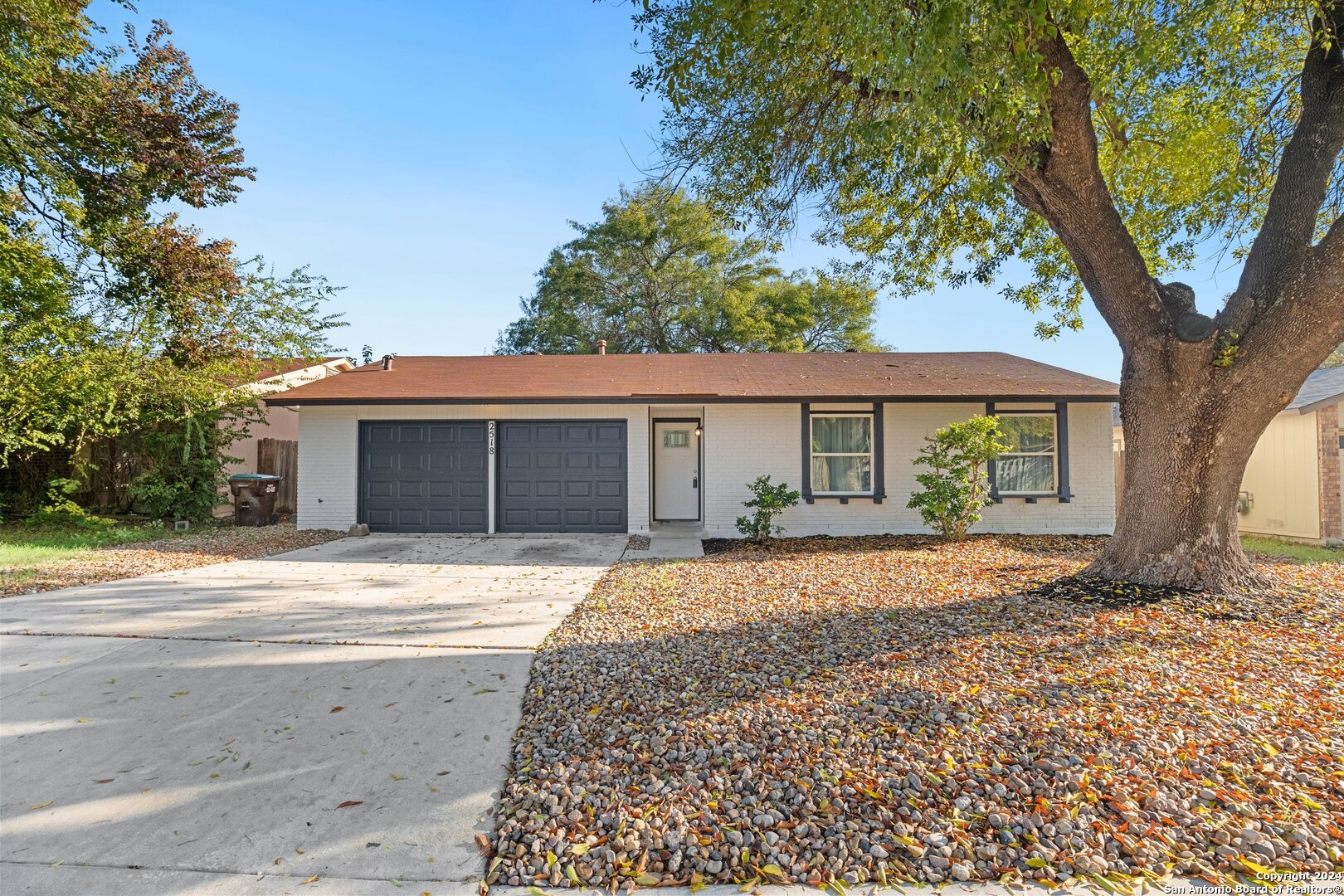 a front view of a house with a garden and trees