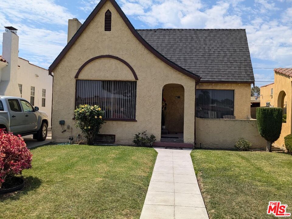 a front view of a house with a yard and potted plants