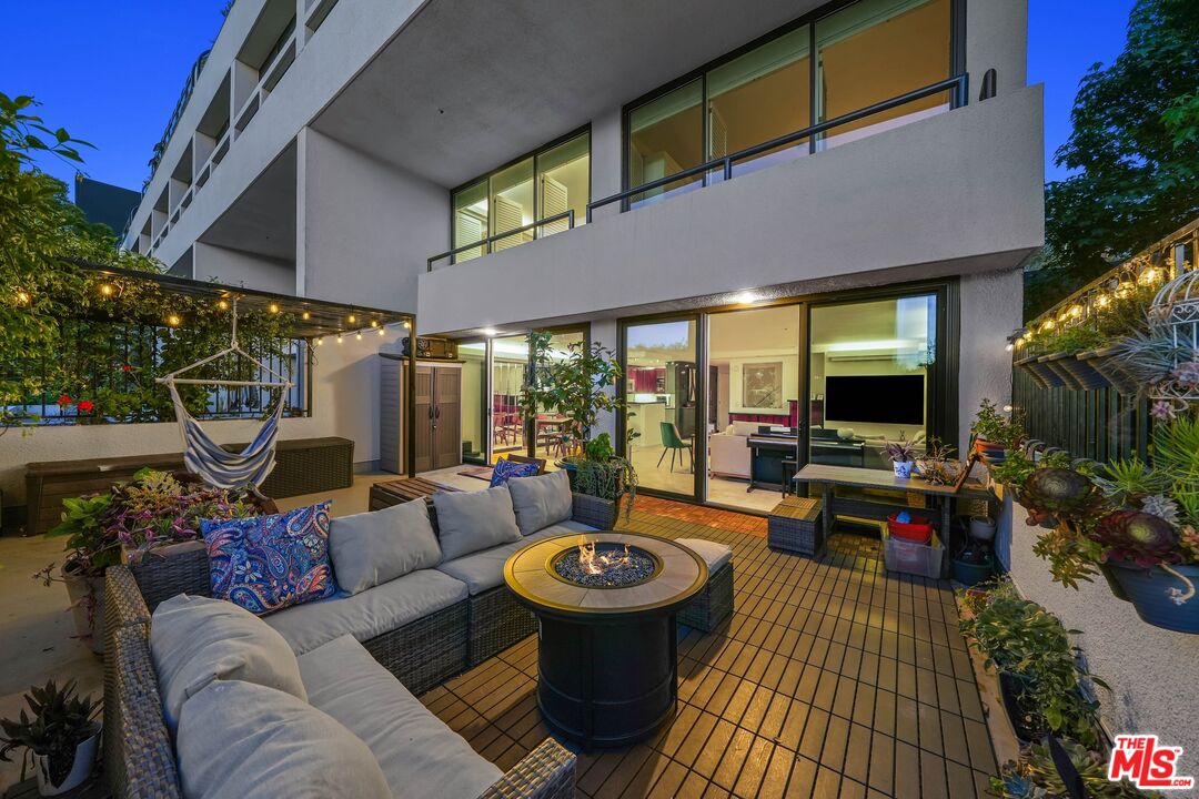 a view of a patio with couches table and chairs under an umbrella with a barbeque grill and couches