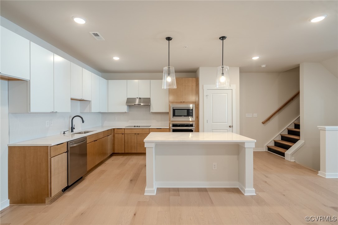 a large kitchen with kitchen island a white counter space a sink stainless steel appliances and cabinets