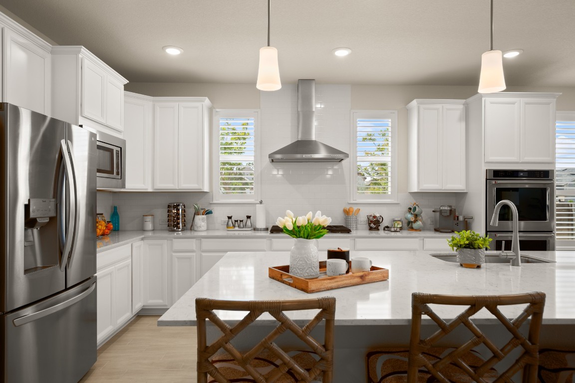 a kitchen with stainless steel appliances a sink a stove a refrigerator a dining table and chairs