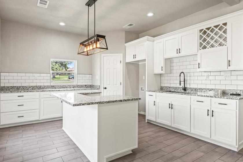 a kitchen with granite countertop cabinets a sink a window and stainless steel appliances