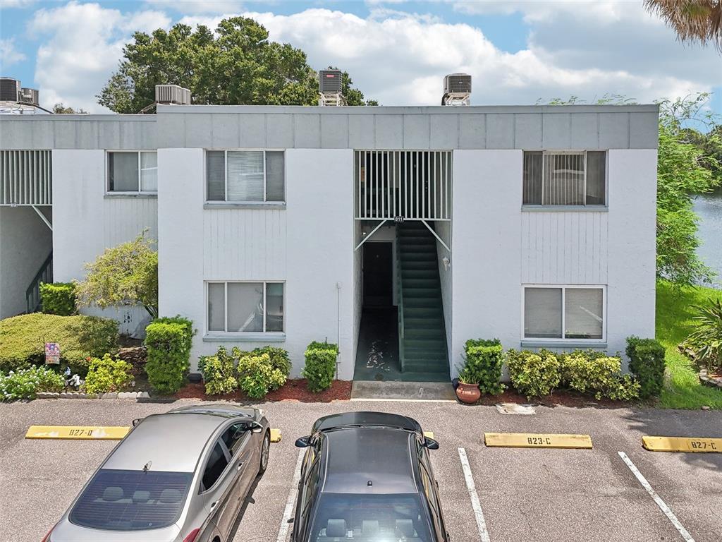 a view of a house with cars park side of road