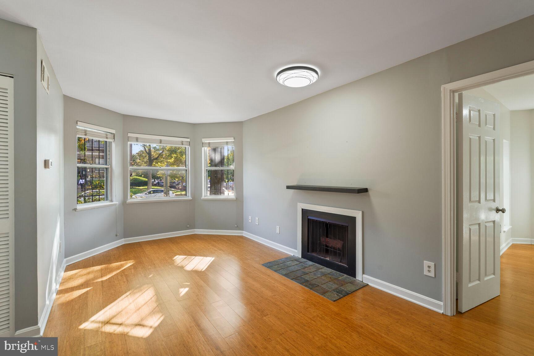 an empty room with windows and fireplace