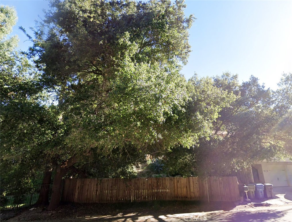 a view of backyard with wooden fence and trees