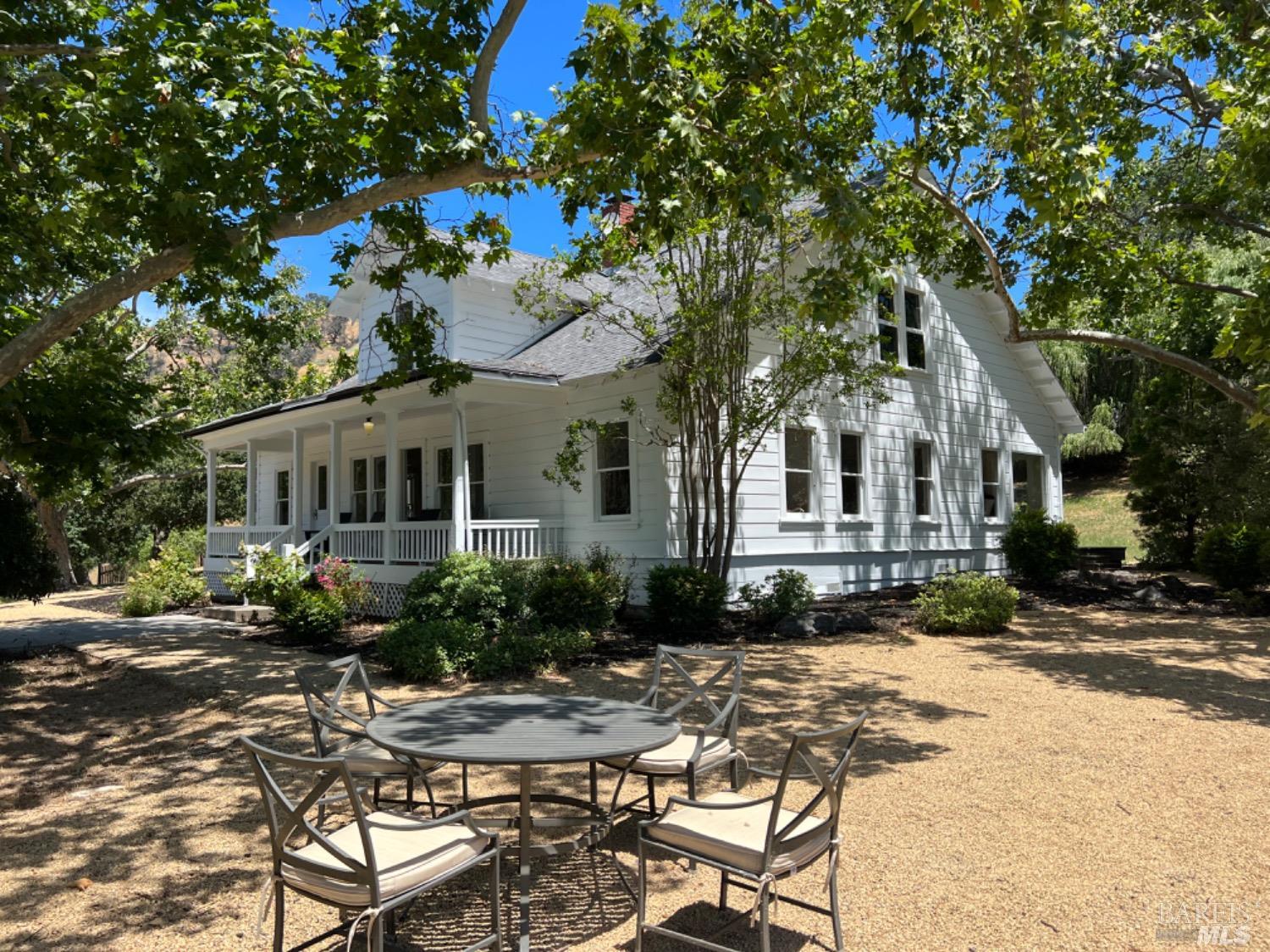 a view of a white house with a chairs in a patio