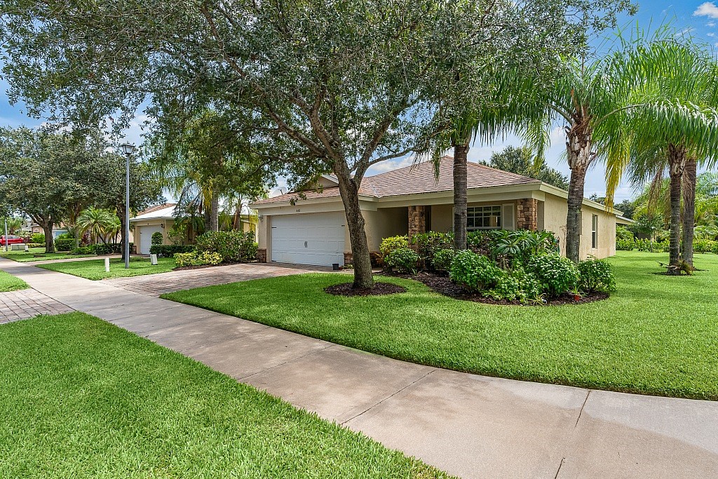 a front view of a house with a yard and palm trees