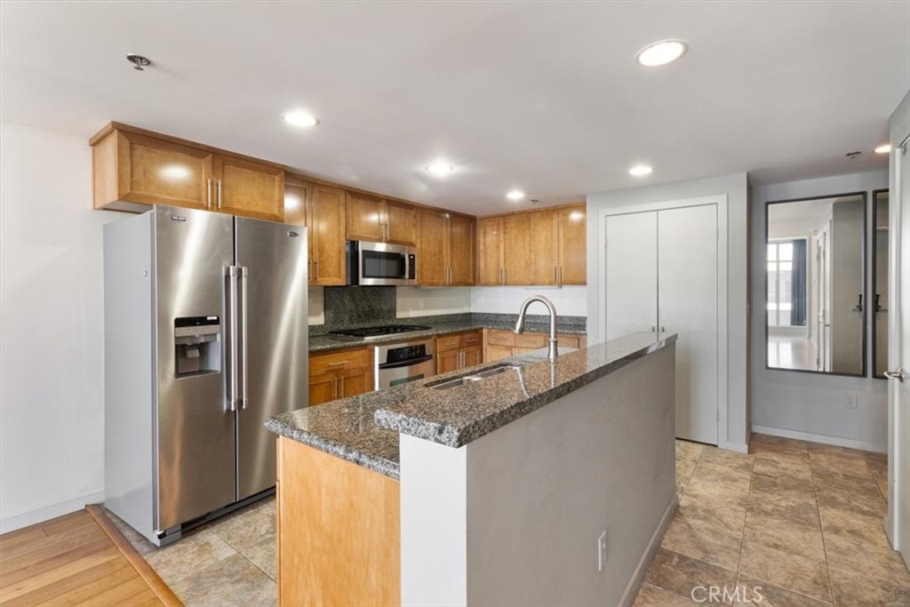 a kitchen with stainless steel appliances granite countertop a refrigerator a stove a sink and a oven