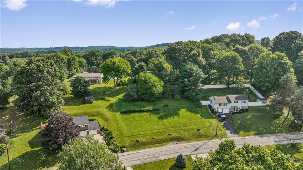 an aerial view of a residential houses with outdoor space and trees all around