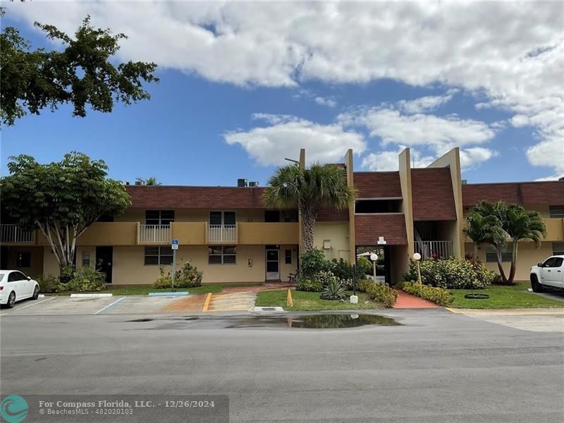 a front view of a building with street view and trees