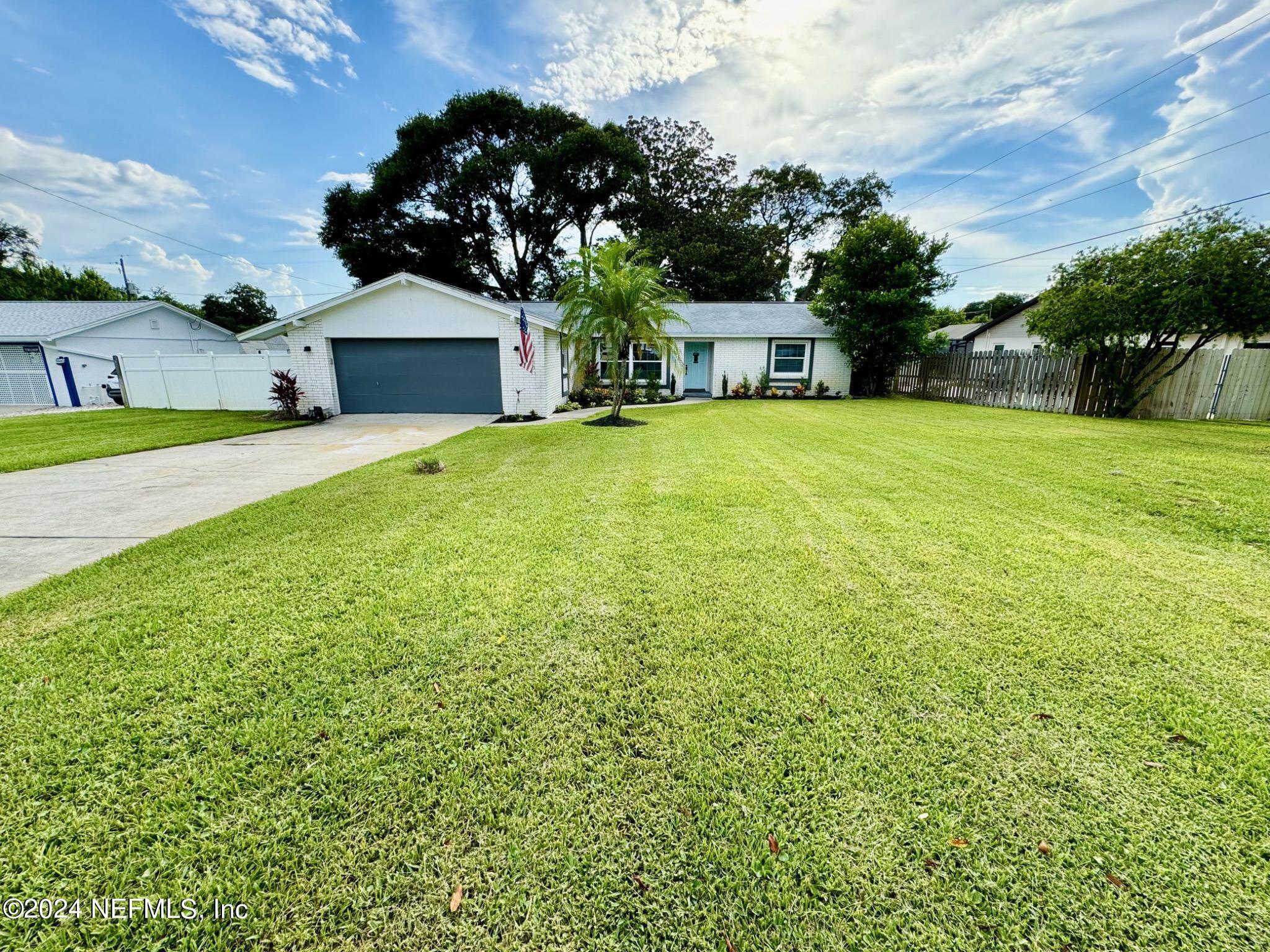 a front view of house with yard and trees in the background