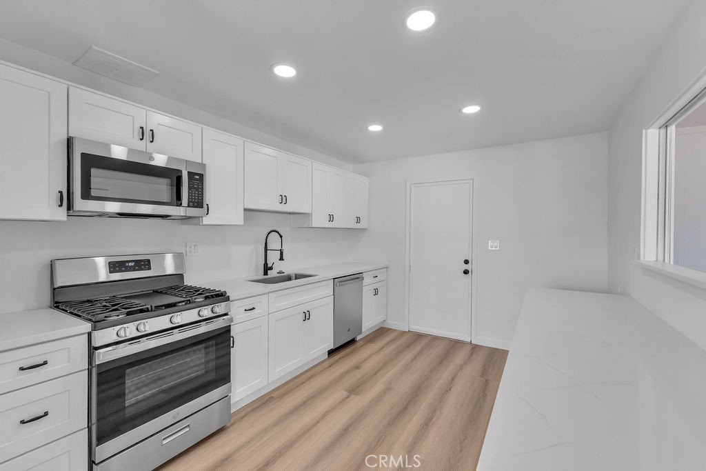 a kitchen with granite countertop a stove top oven sink and cabinets