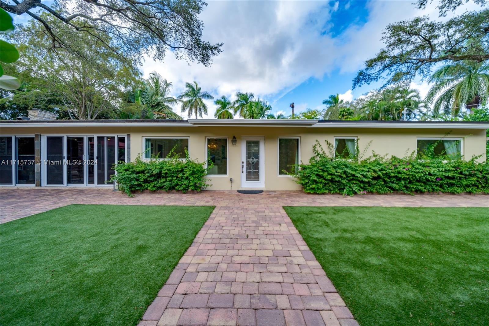 a front view of a house with a yard and potted plants