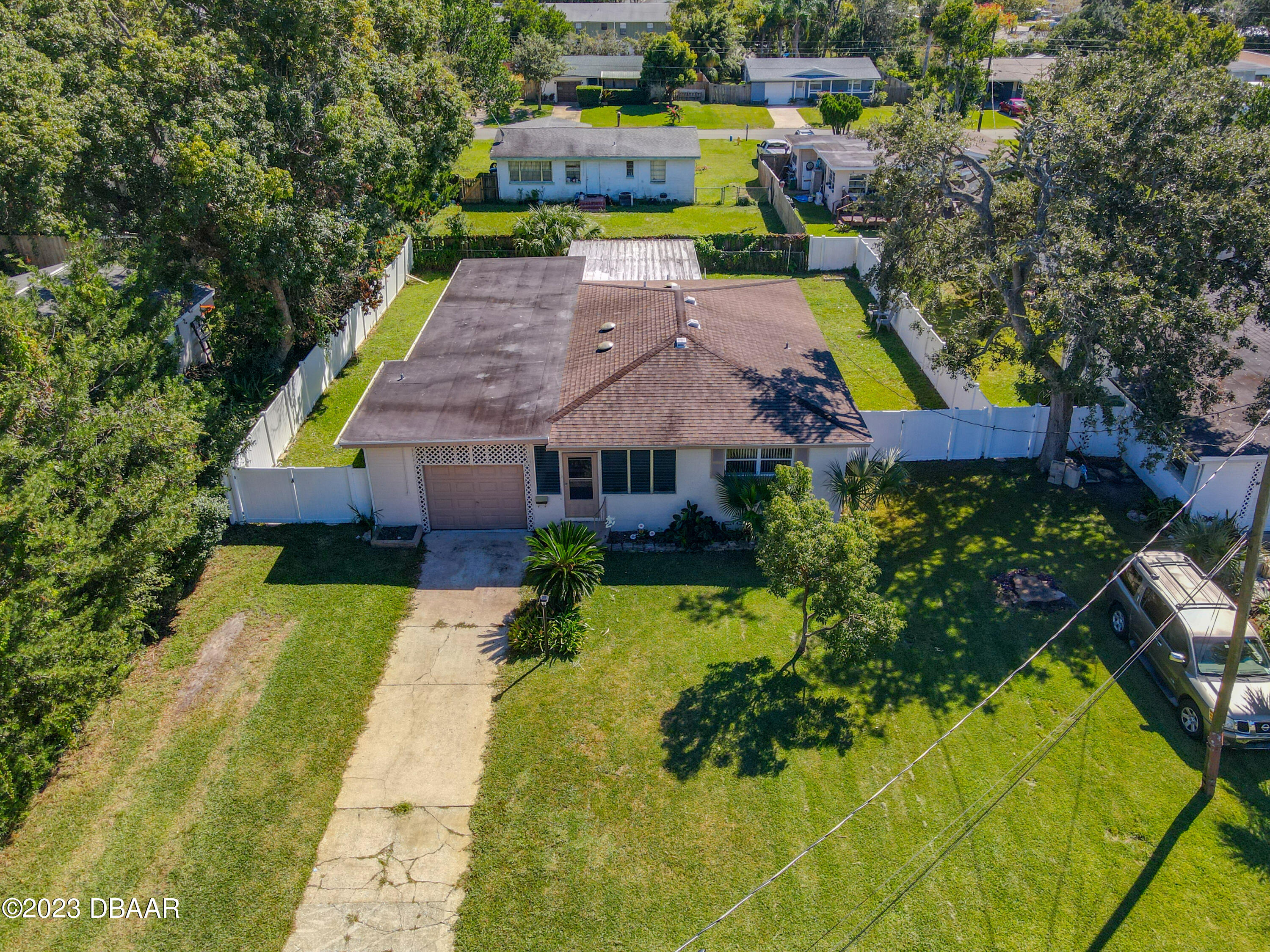 an aerial view of a house with swimming pool and large trees