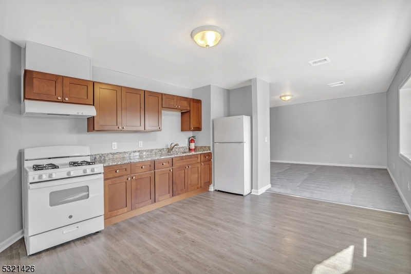 a kitchen with a refrigerator a stove top oven and wooden floors