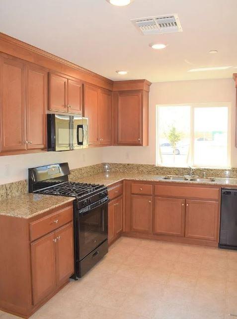 a kitchen with stainless steel appliances granite countertop a stove a sink and a microwave