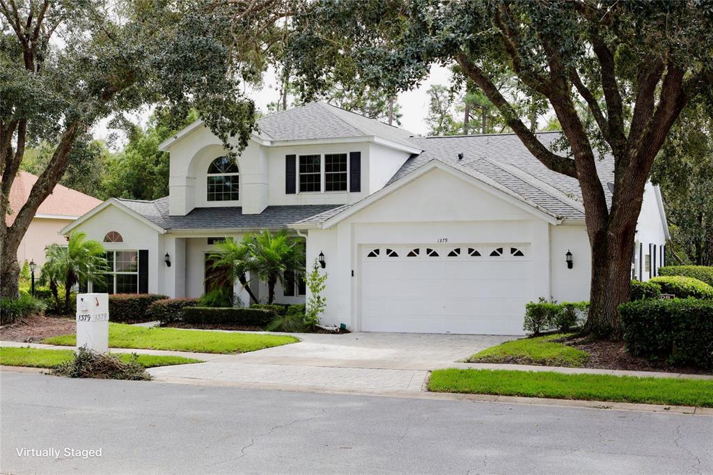 a view of a white house with a big yard plants and large trees