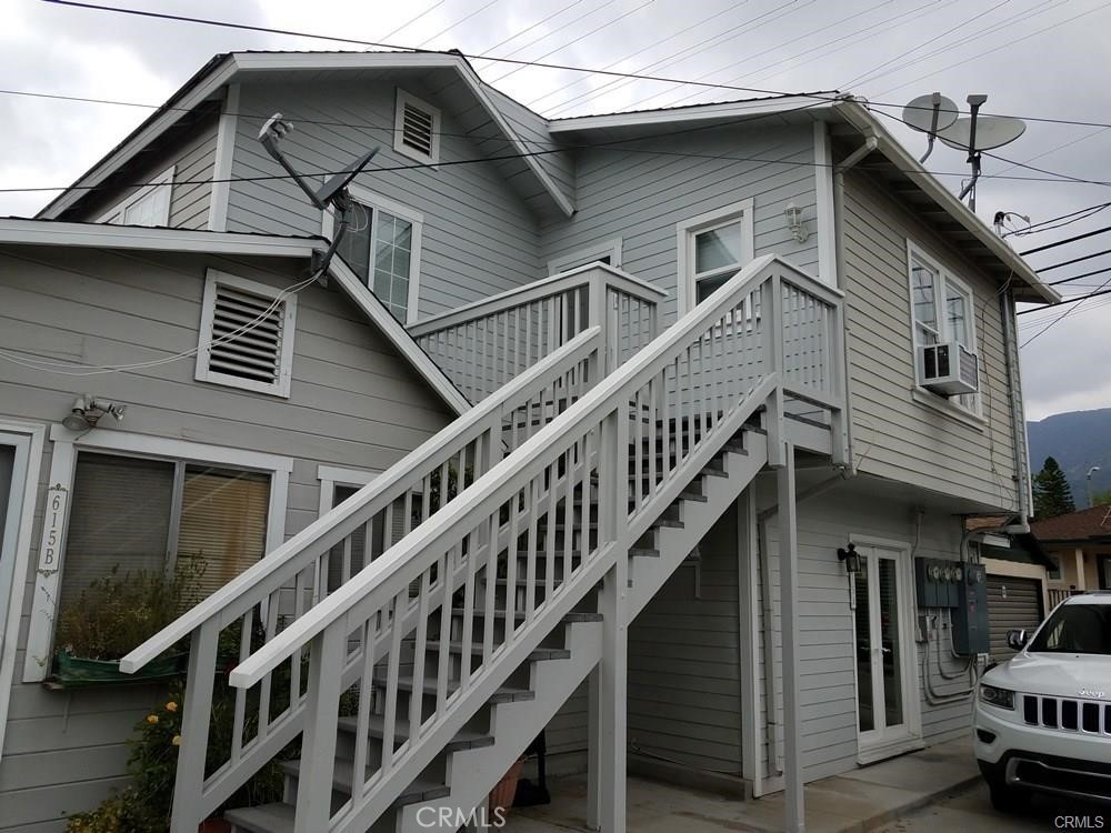 a view of a house with wooden stairs and a large tree