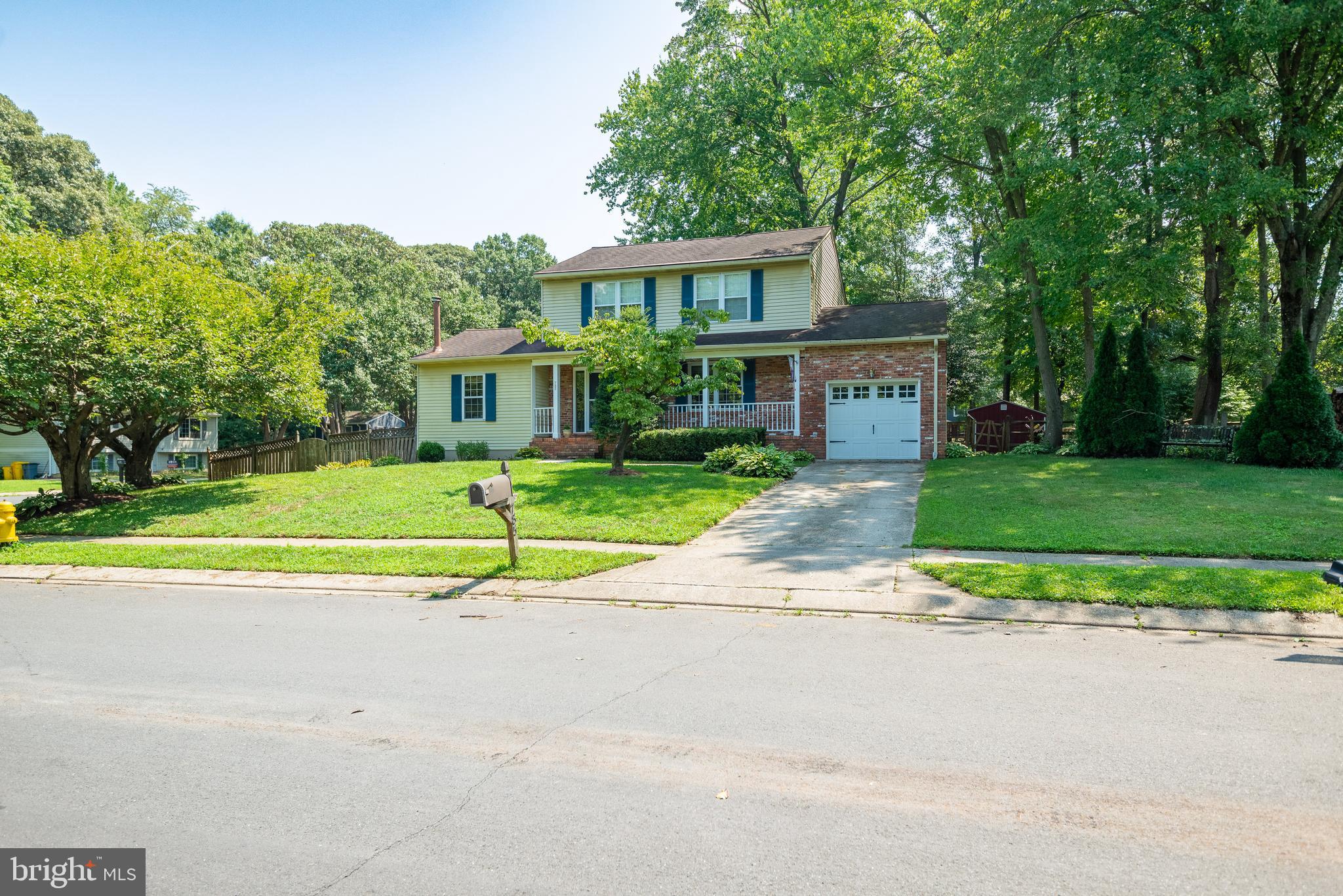 a view of house with a big yard and large trees