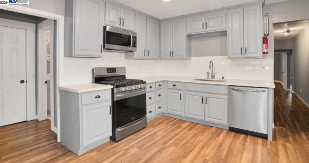 a kitchen with cabinets stainless steel appliances and wooden floor