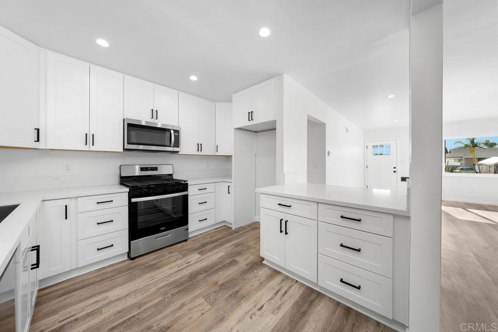 a kitchen with granite countertop a refrigerator stove and white cabinets