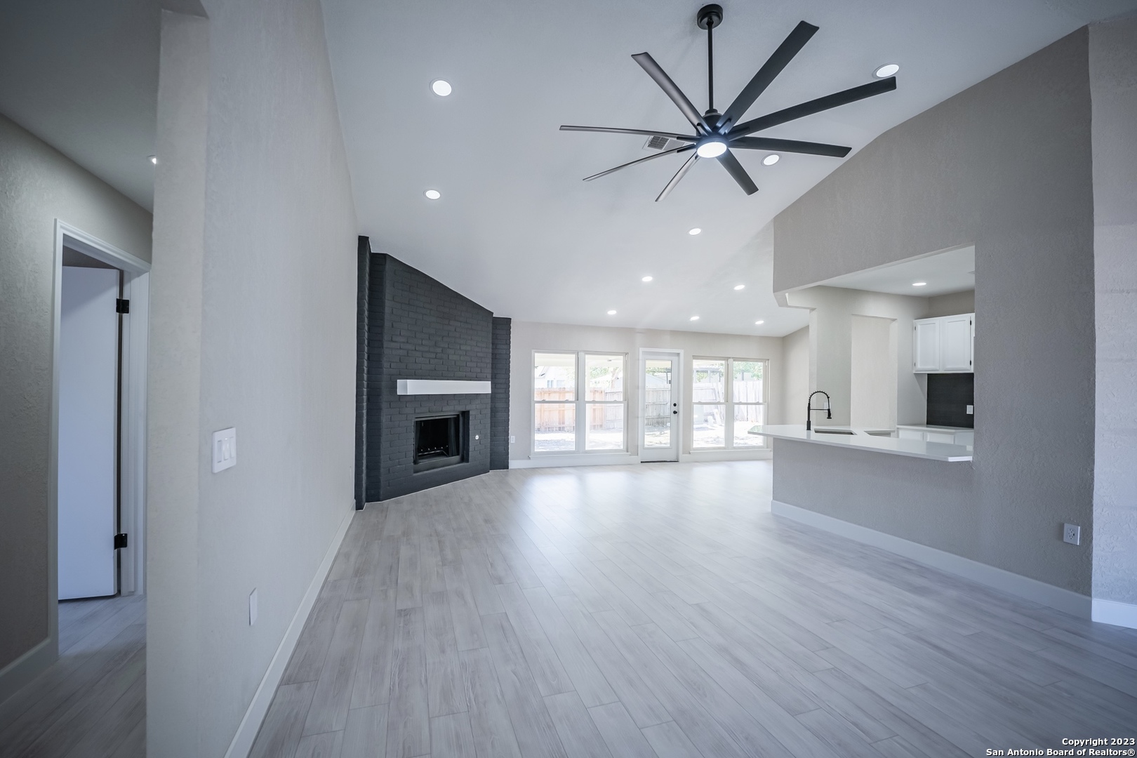 a view of an empty room with a fireplace and a ceiling fan