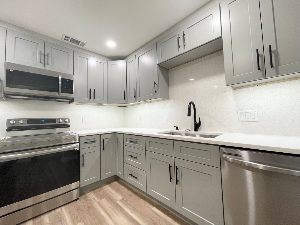 a kitchen with sink a microwave and cabinets