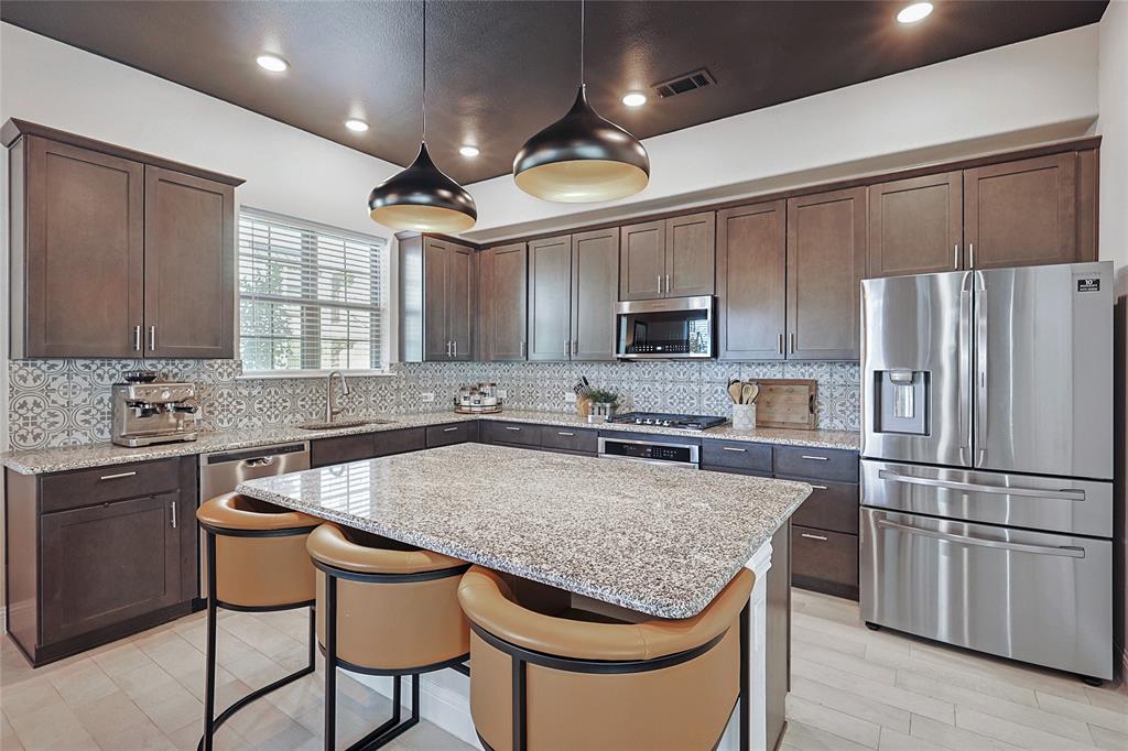 a kitchen with stainless steel appliances granite countertop a table chairs sink refrigerator and microwave