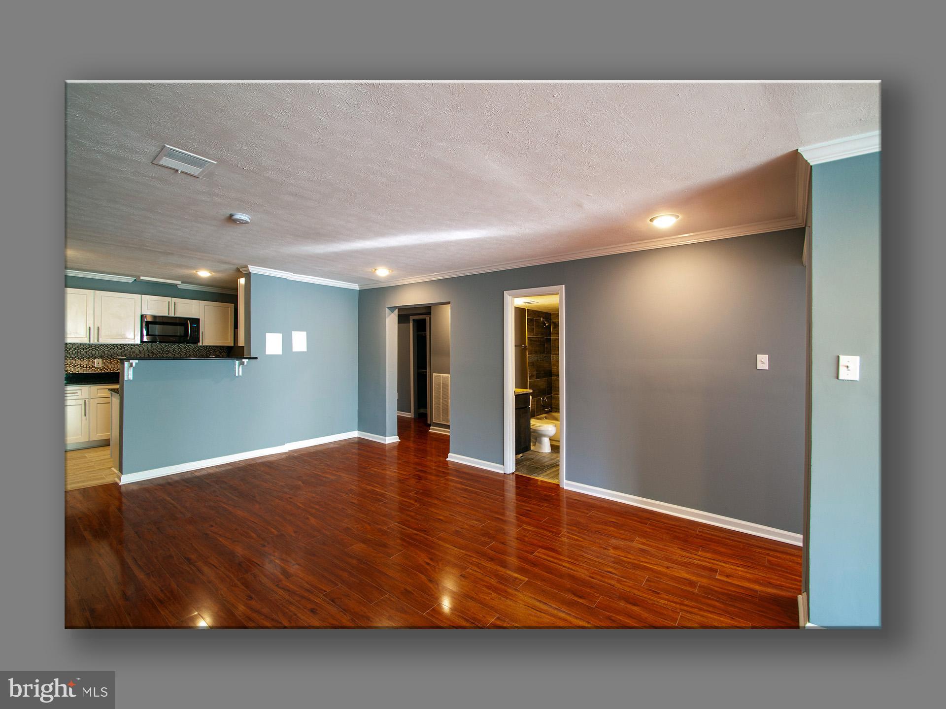 a view of an empty room with kitchen and a window