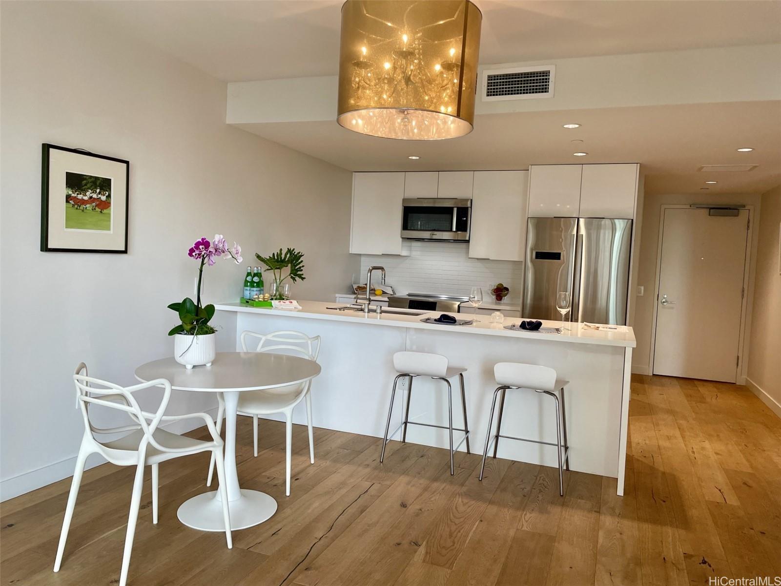 a kitchen with stainless steel appliances granite countertop a dining table chairs and a refrigerator