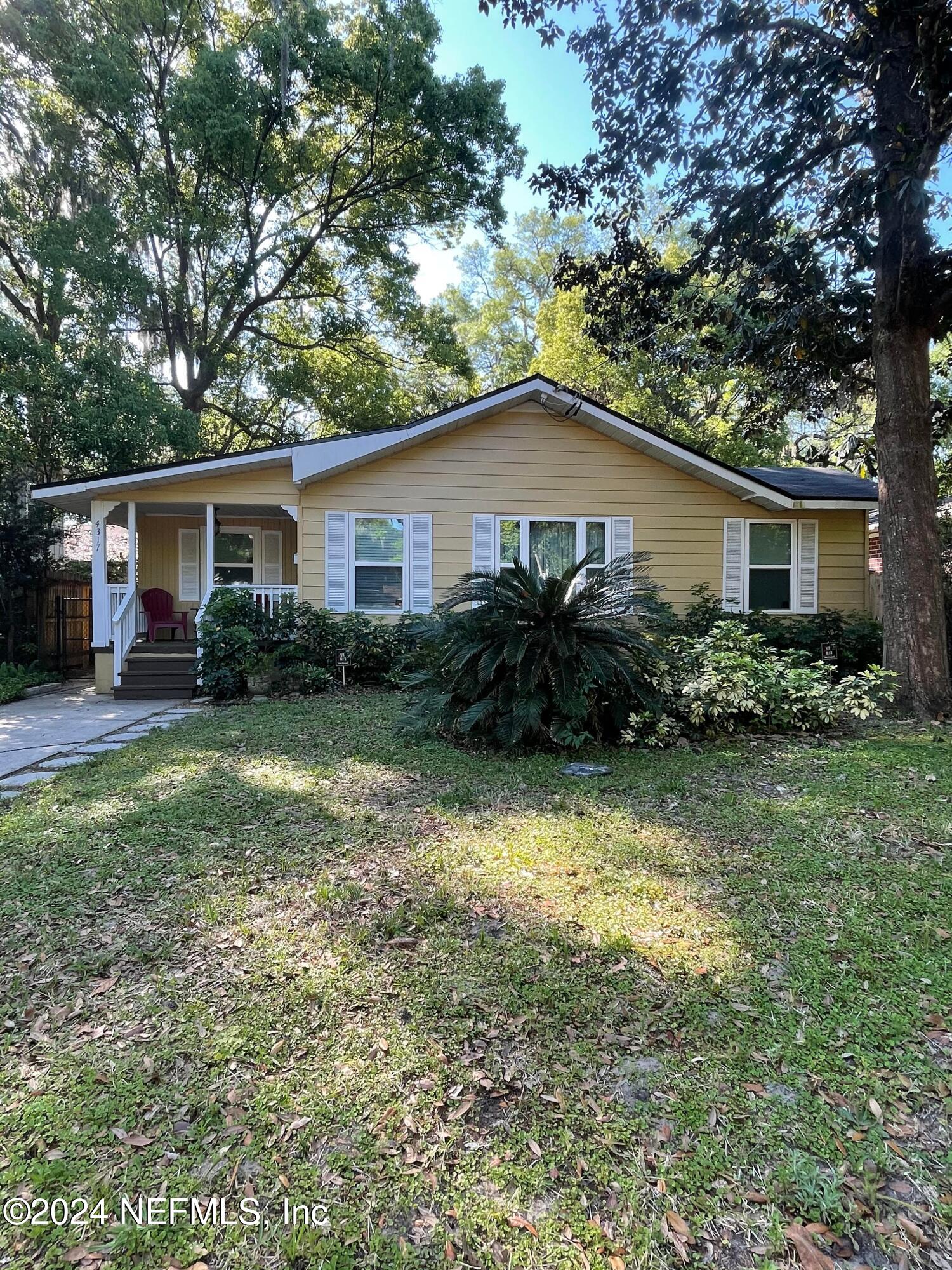 a backyard of a house with large trees and plants