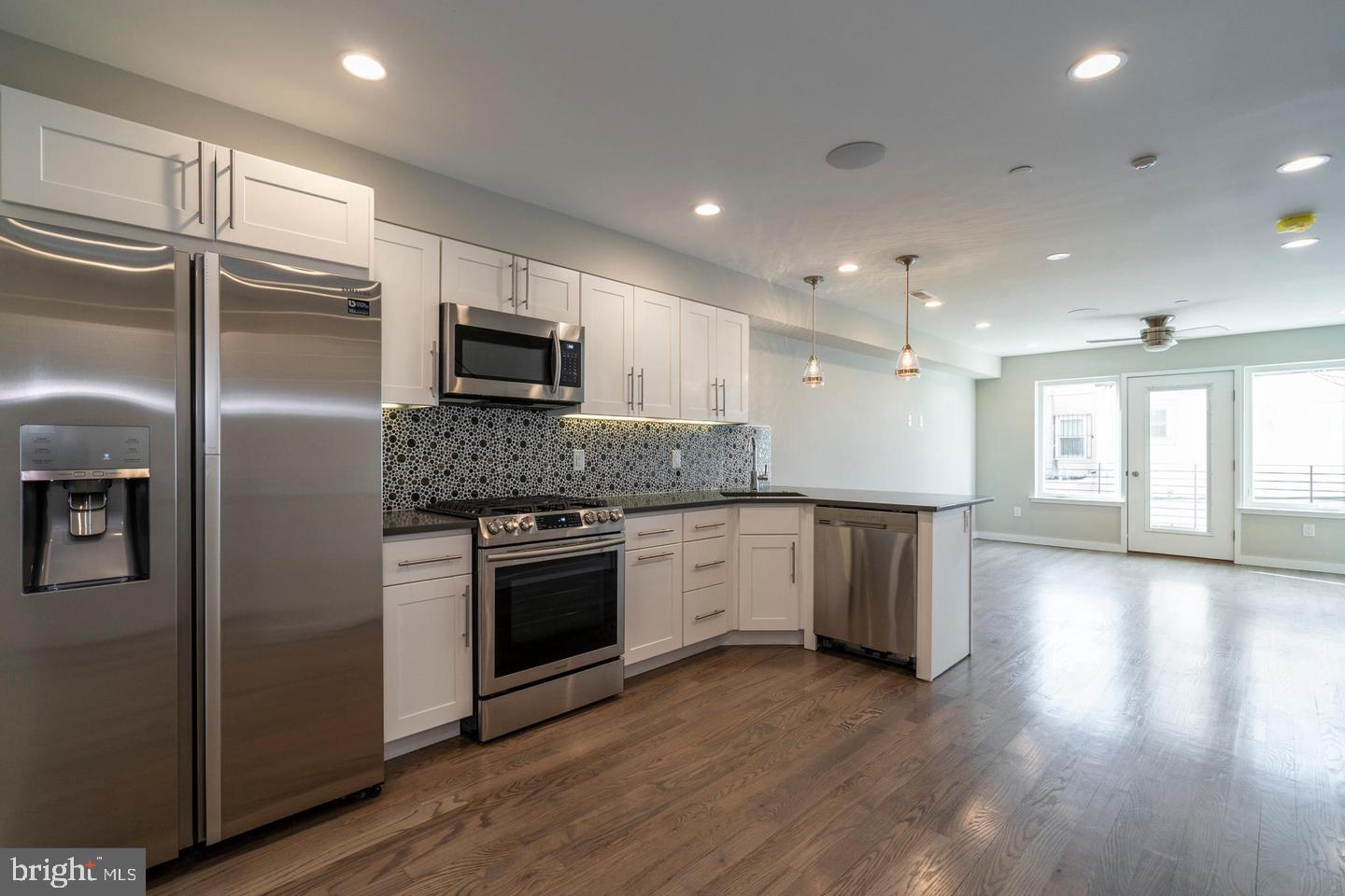 a kitchen with granite countertop a refrigerator and a stove top oven