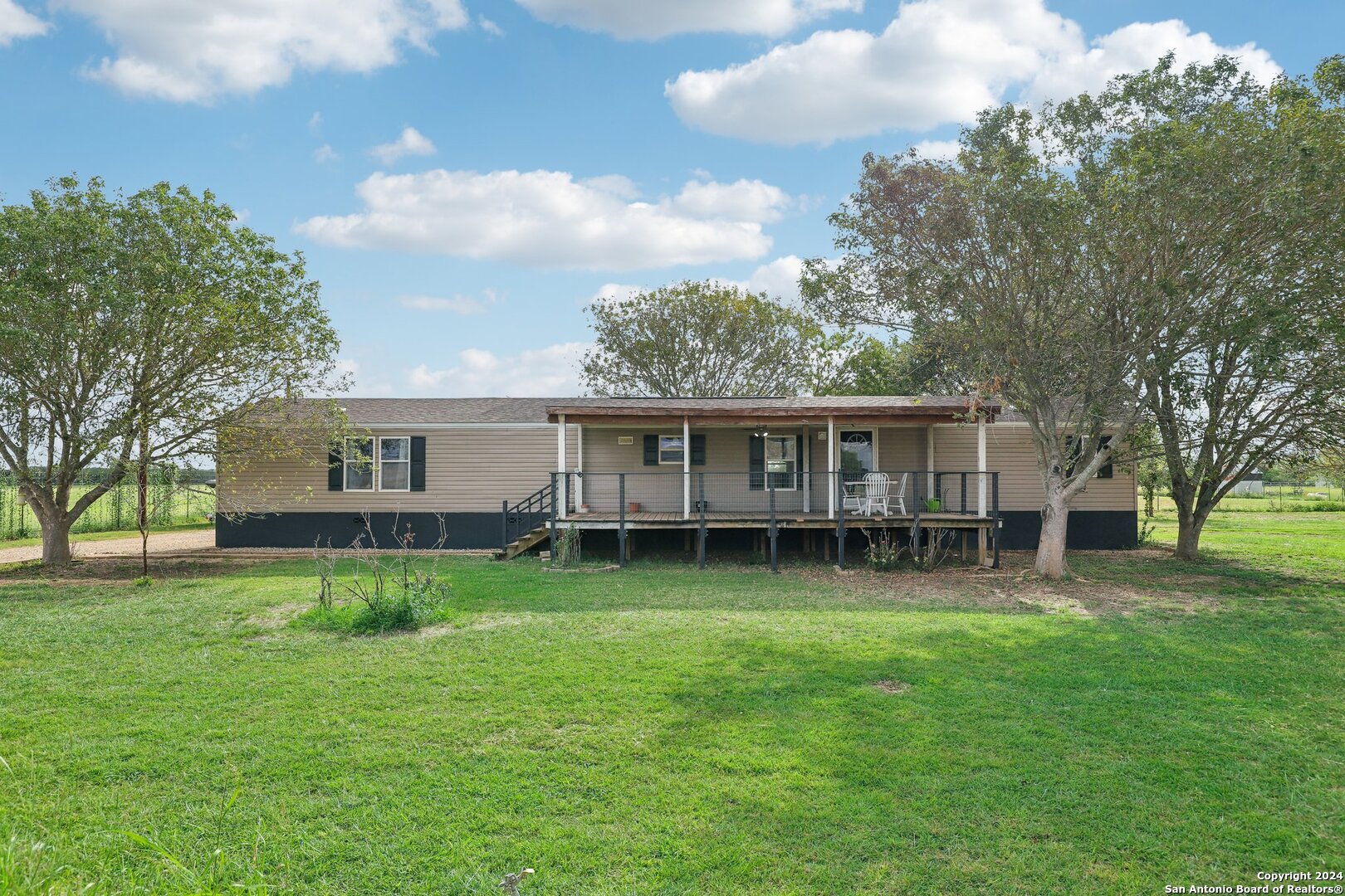 a view of a house with a big yard and large trees