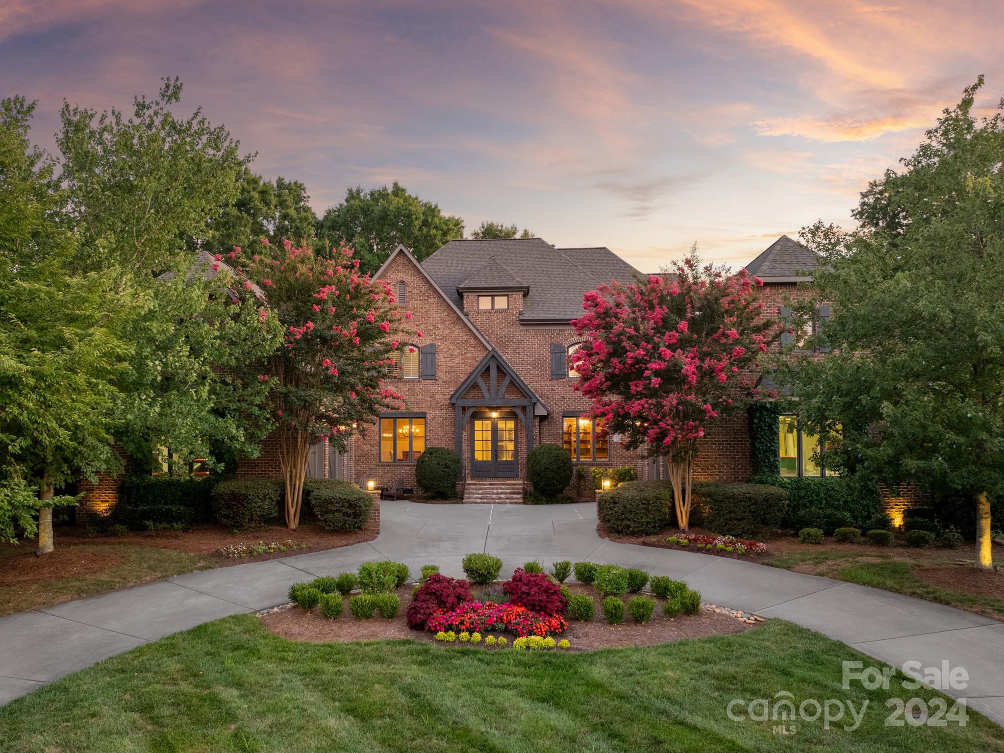 a front view of a house with a big yard and a large tree