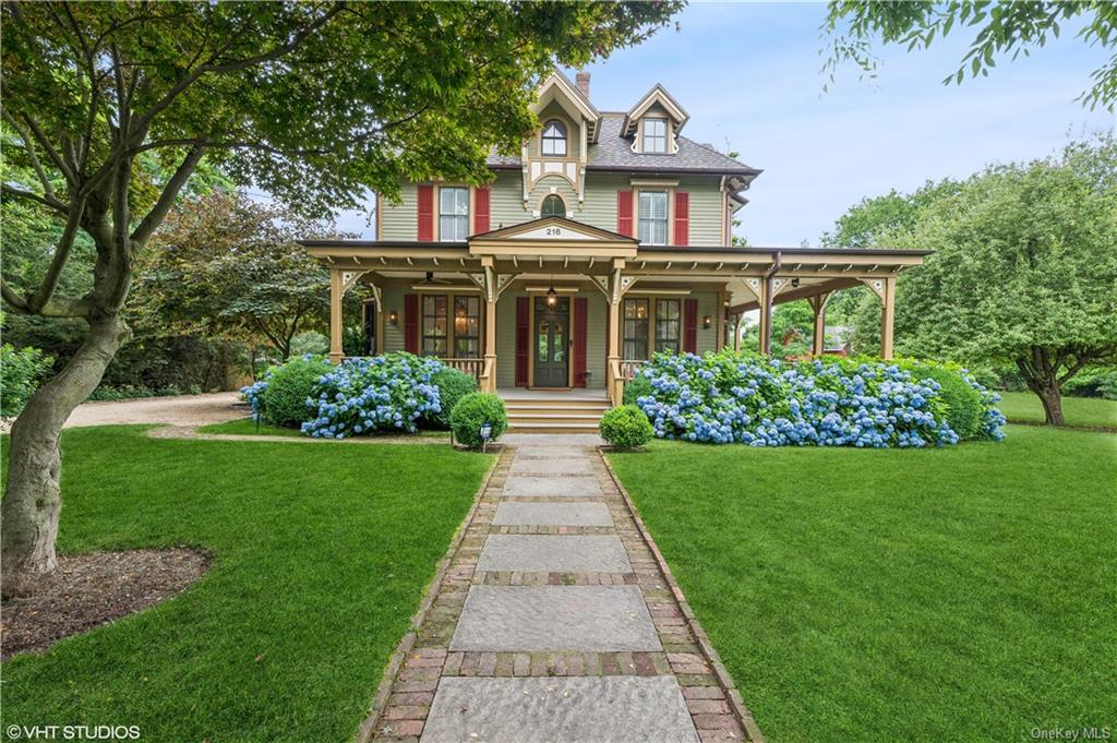 Victorian home with lovely wraparound verandas and lush front lawn