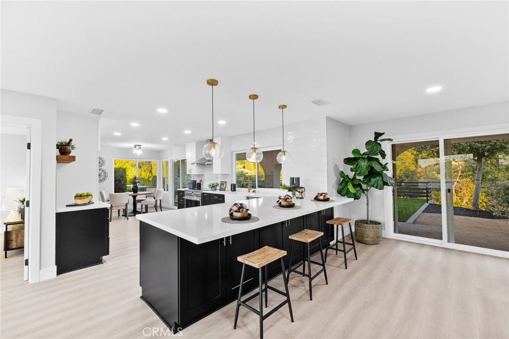 a dining hall with stainless steel appliances kitchen island granite countertop a table chairs and a counter top space