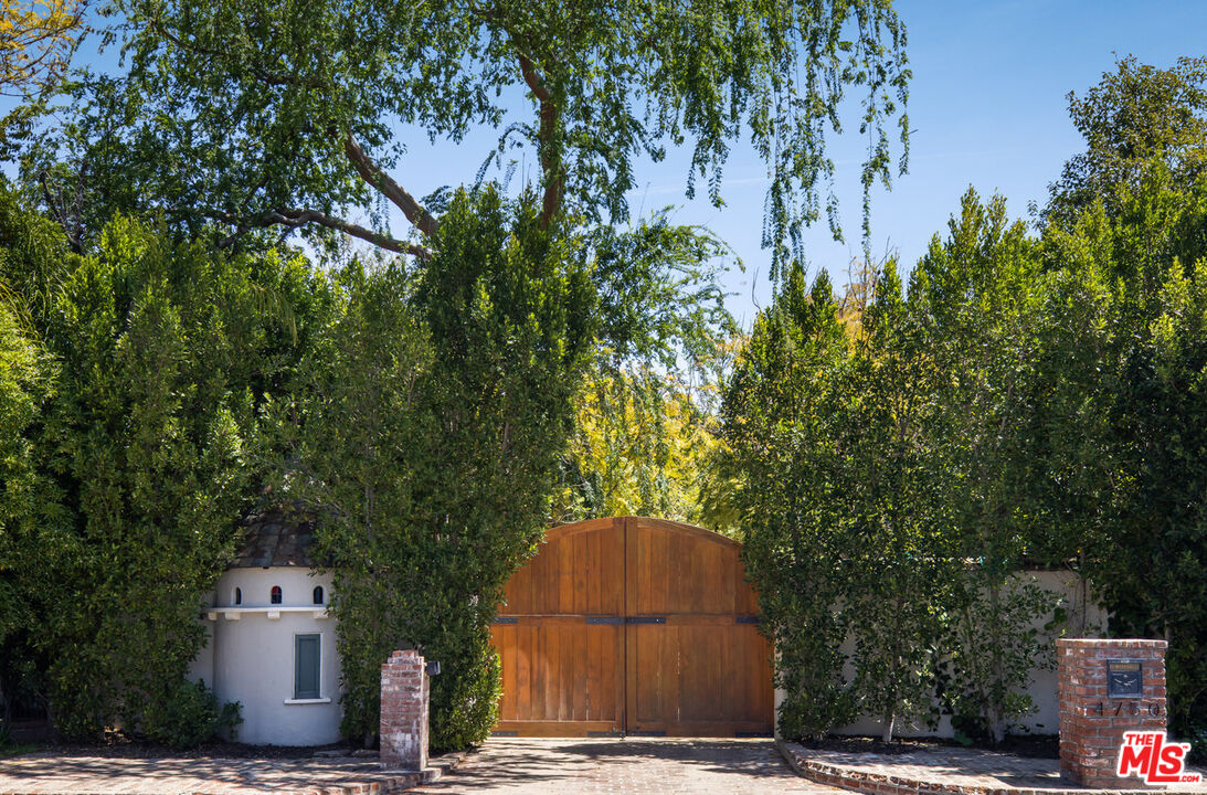 a backyard of a house with large trees and plants