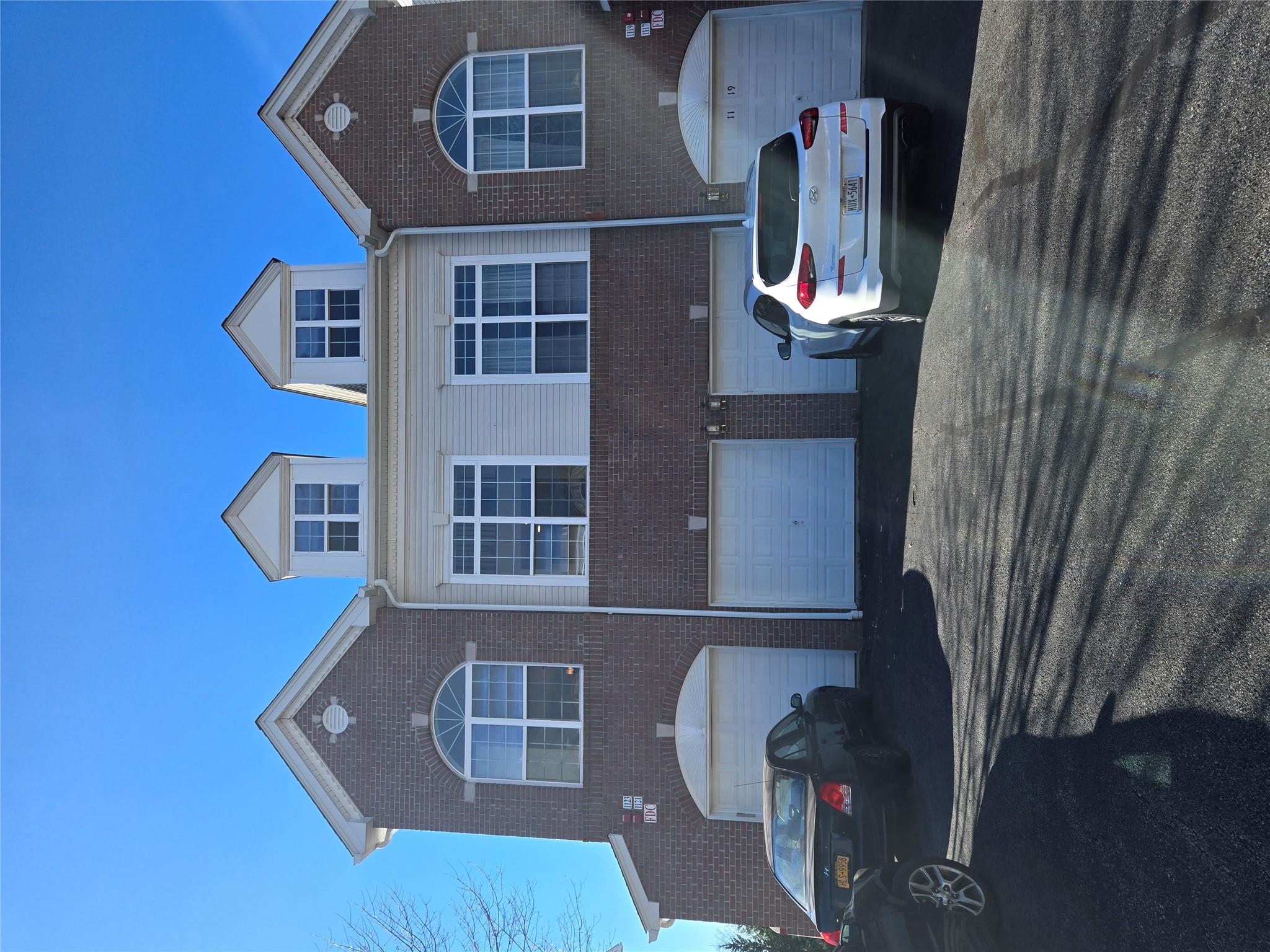 Front of the condo with one car garage (second door from left) and driveway