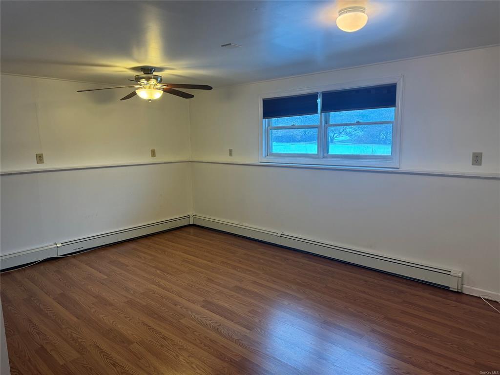 Spare room featuring ceiling fan, dark hardwood / wood-style flooring, and a baseboard radiator