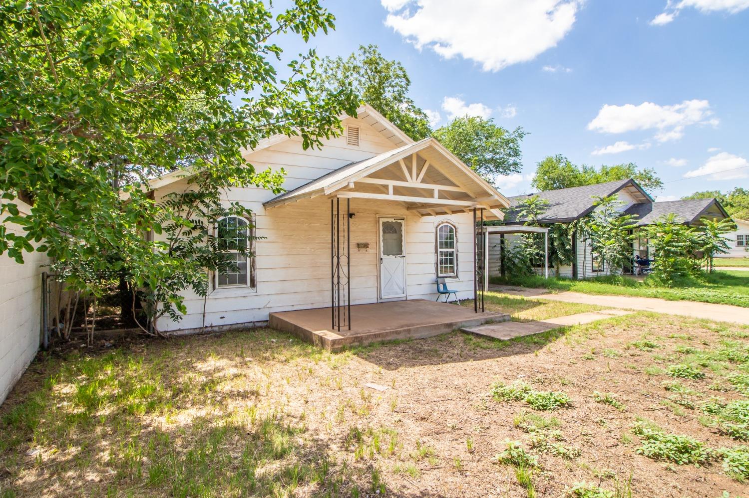 a view of a house with a yard and large tree