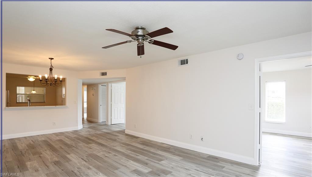 Empty room featuring ceiling fan with notable chandelier and light hardwood / wood-style flooring