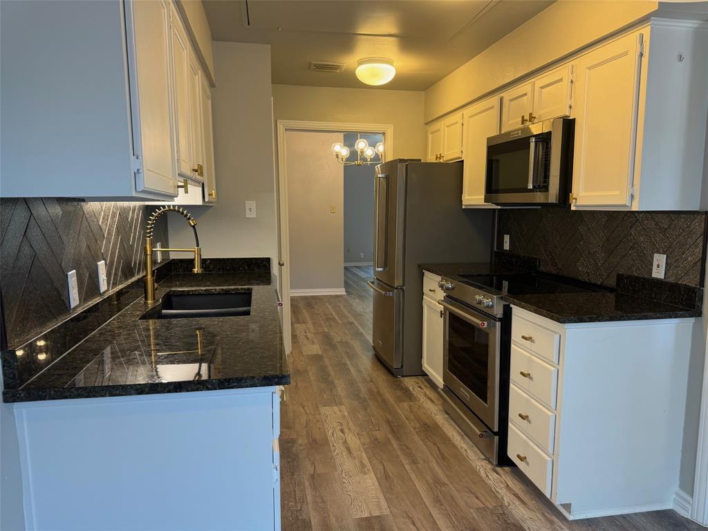 a kitchen with granite countertop a refrigerator and a stove top oven