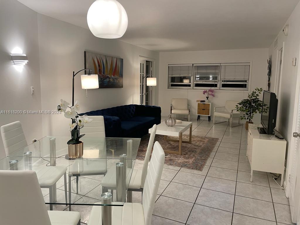 a living room with furniture a flat screen tv and kitchen view