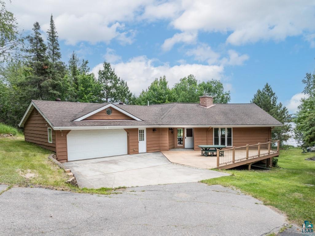 Single story home with a wooden deck, a garage, and a front yard