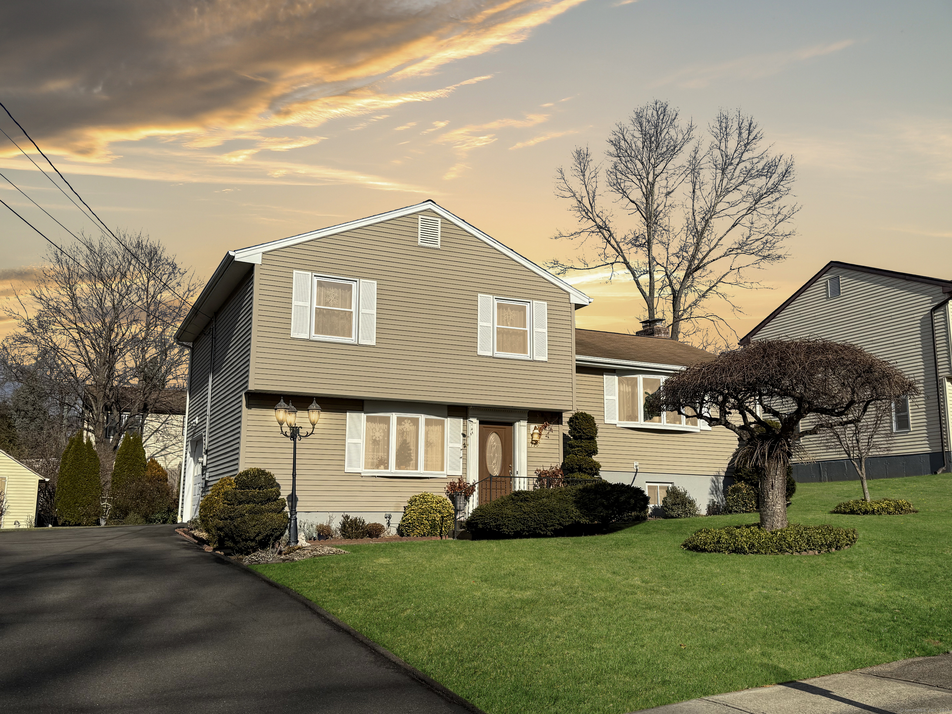 a front view of a house with a garden and tree