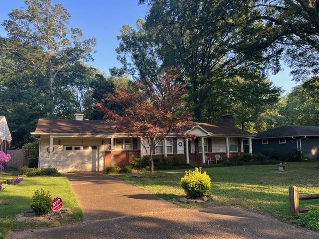 a front view of a house with a garden and trees