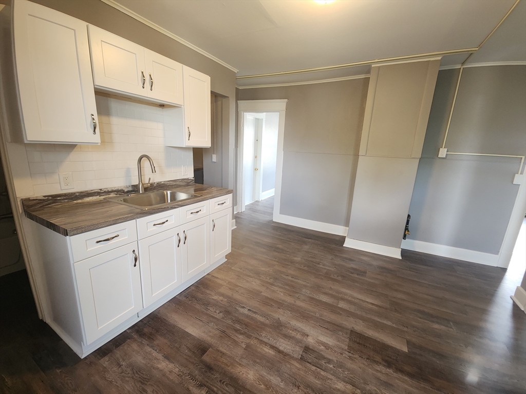 a kitchen with a sink cabinets and wooden floor